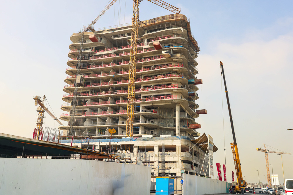 Beach Walk Iii By Imtiaz A construction site featuring a multi-story building with cranes and scaffolding against a cloudy sky.
